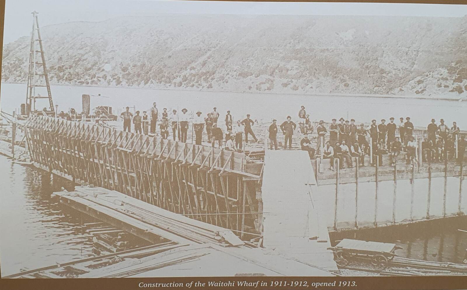 The Waitohi wharf under construction, a long line of men standing on it
